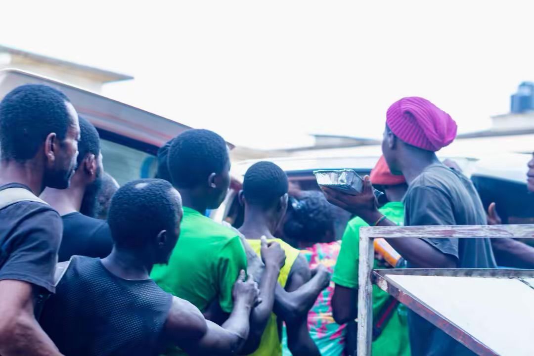 Community members gather at the back of a van as volunteers hand out supplies