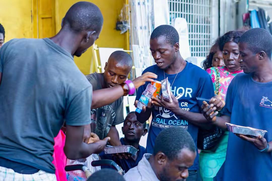 Volunteers handing out drinks and meals to a group of men