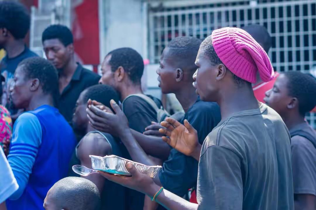 Young men wait to receive packed meals during a street outreach