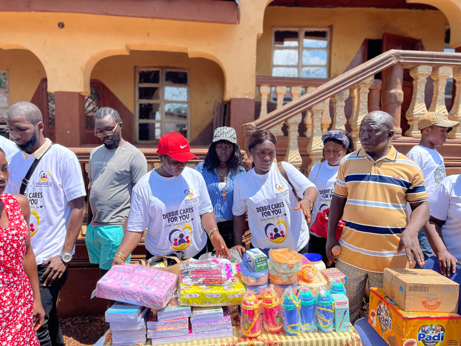 Volunteers in Debbie Cares T-shirts sort exercise books, pencils and drink bottles on a table
