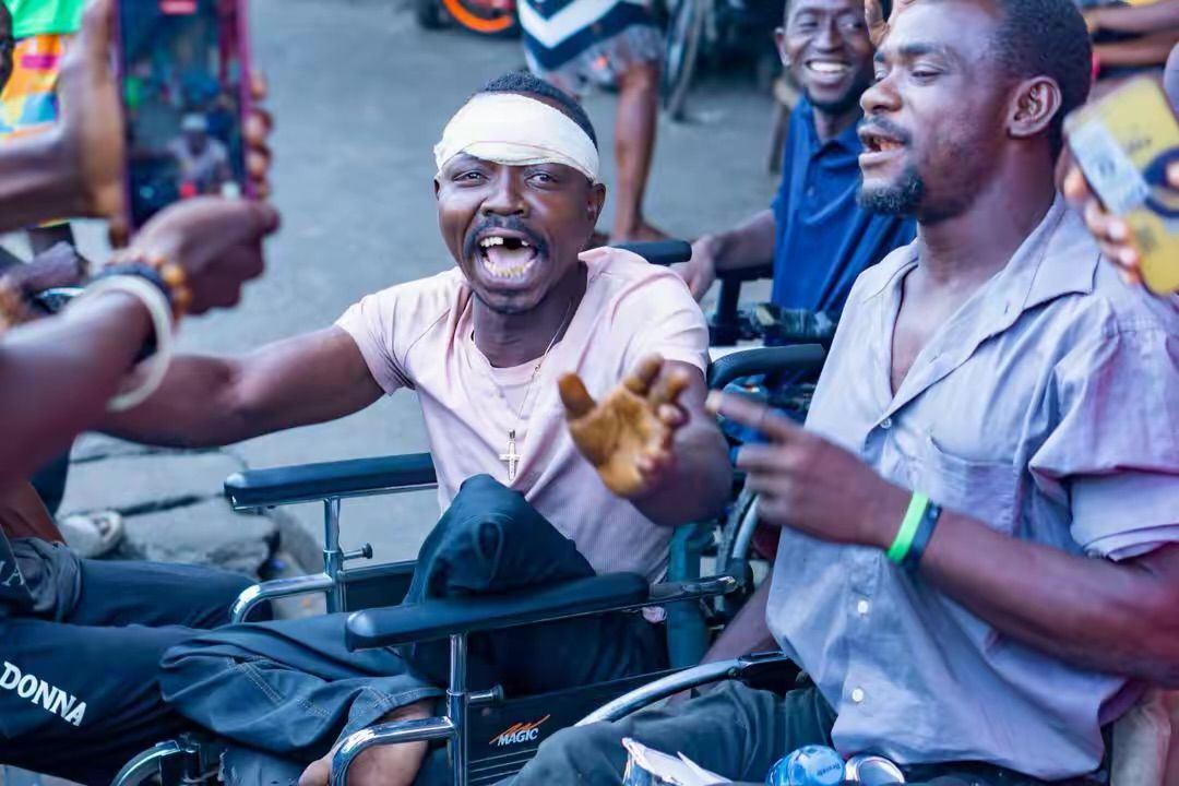 A man in a wheelchair laughing with volunteers